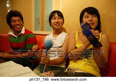 Stock Photograph - Teenagers singing at a karaoke bar. Fotosearch