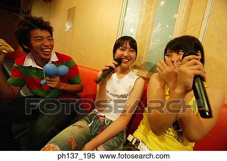 Stock Photography - Teenagers singing at a karaoke bar. Fotosearch