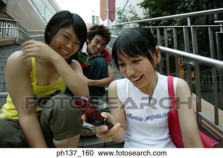 Teenagers sitting together operating their mobile phones View Large Photo Image Stock Image - Teenagers sitting together operating their mobile phones. Fotosearch