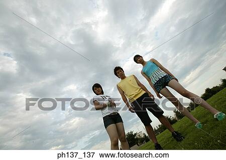 Teenagers standing on a lawn View Large Photo Image Stock Photo - Teenagers standing on a lawn. Fotosearch
