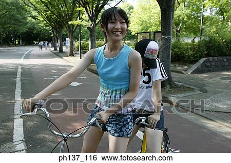 Stock Photograph - Two Teenage girls riding a tandem bicycle. Fotosearch