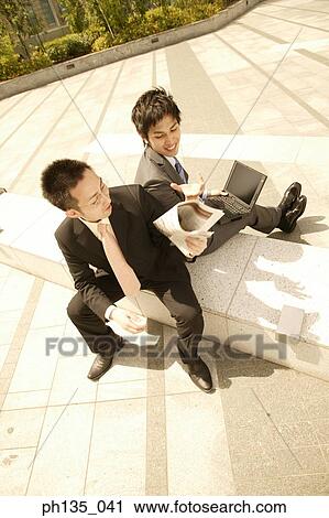 High angle view of two young businessmen sitting outdoors and talking View Large Photo Image Stock Image - High angle view of two young businessmen sitting outdoors and talking. Fotosearch