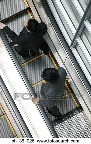 High angle view of two young businessmen on an escalator View Large Photo Image Stock Photograph - High angle view of two young businessmen on an escalator. Fotosearch