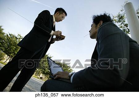Low angle view of two young businessmen working outdoors View Large Photo Image Stock Photo - Low angle view of two young businessmen working outdoors. Fotosearch