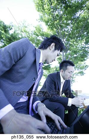 Stock Photography - Low angle view of two young businessmen working outdoors. Fotosearch