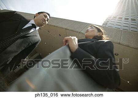 Low angle view of young business executives talking outside a building View Large Photo Image Stock Photograph - Low angle view of young business executives talking outside a building. Fotosearch