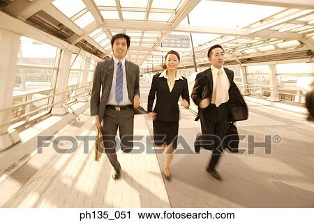 Three executives running in a passageway View Large Photo Image Stock Image - Three executives running in a passageway. Fotosearch