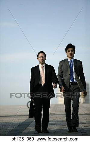 Two young businessmen walking outdoors View Large Photo Image Stock Photo - Two young businessmen walking outdoors. Fotosearch