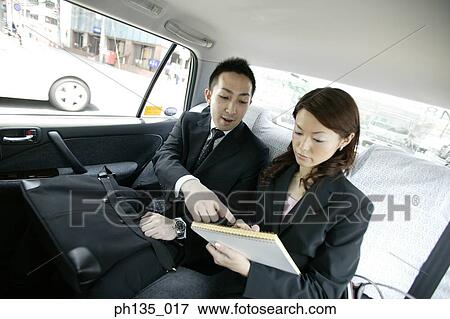 Stock Photo - Young business executives discussing business in a car. Fotosearch