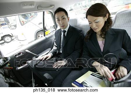 Stock Photo - Young business executives discussing business in a car. Fotosearch