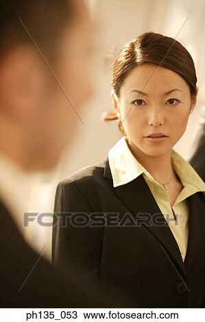 Stock Image - Young businesswoman looking at a man. Fotosearch