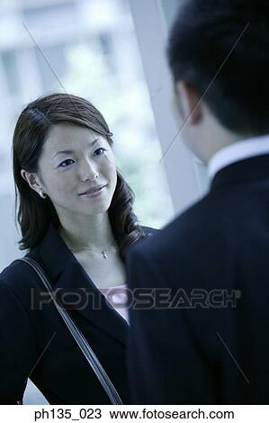 Young businesswoman talking to a young businessman standing across her View Large Photo Image Stock Image - Young businesswoman talking to a young businessman standing across her. Fotosearch