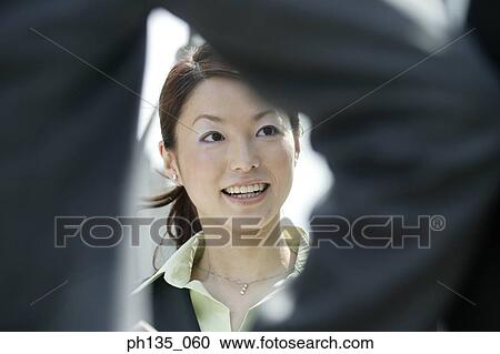 Stock Image - Young businesswoman talking to a young businessman standing across her. Fotosearch