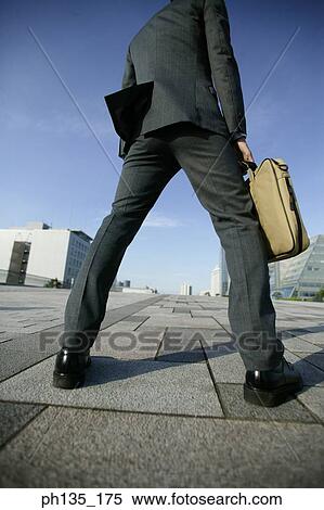 Stock Photography - Low angle view of a young businessman holding a briefcase. Fotosearch