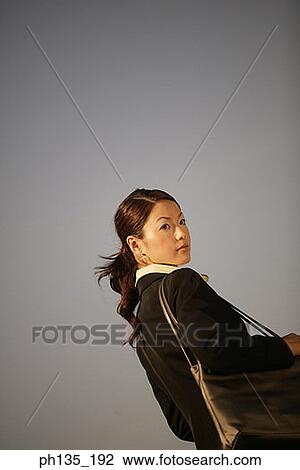 Stock Image - Rear view of a young businesswoman carrying a shoulder bag. Fotosearch