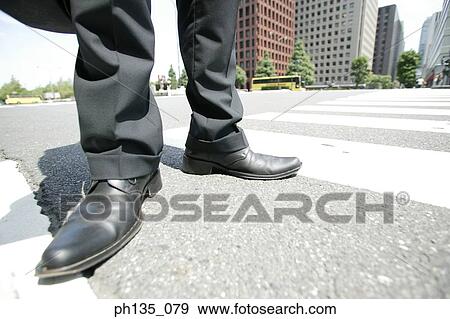 View of the feet of a man standing on a street crossing View Large Photo Image Stock Photo - View of the feet of a man standing on a street crossing. Fotosearch