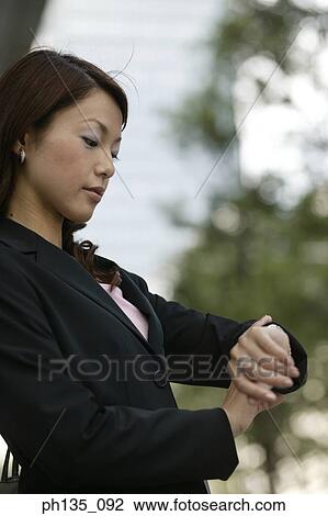 Young businesswoman looking at her wrist watch View Large Photo Image Stock Image - Young businesswoman looking at her wrist watch. Fotosearch