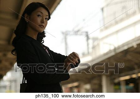 Young businesswoman looking at her wrist watch View Large Photo Image Stock Image - Young businesswoman looking at her wrist watch. Fotosearch