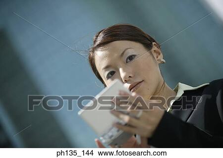 Young businesswoman operating a hand held device View Large Photo Image Picture - Young businesswoman operating a hand held device. Fotosearch