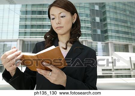 Stock Image - Young businesswoman reading a diary. Fotosearch