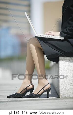 Young businesswoman sitting operating a laptop computer View Large Photo Image Stock Photo - Young businesswoman sitting operating a laptop computer. Fotosearch