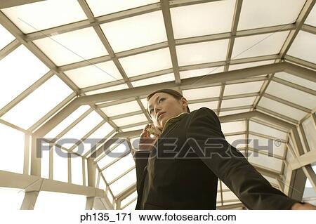 Stock Image - Young businesswoman standing talking on a mobile phone. Fotosearch
