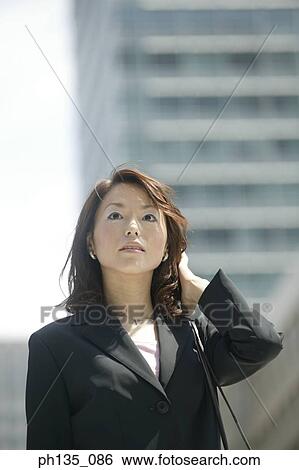 Stock Photograph - Young businesswoman standing with her hand on her head. Fotosearch
