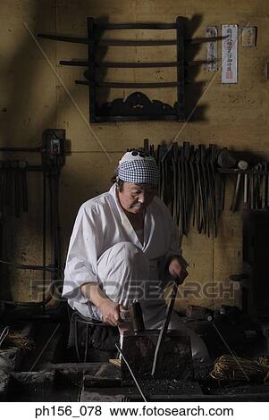 Stock Photo - Blacksmith working on a sword in a workshop. Fotosearch
