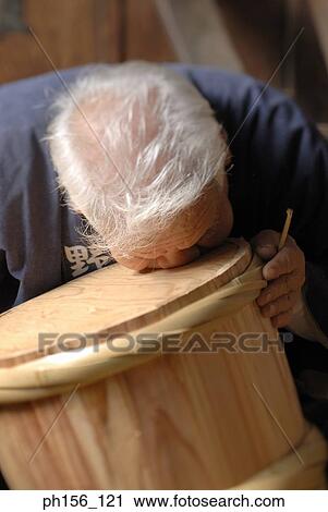Stock Image - Close-up of a carpenter blowing air into a barrel. Fotosearch
