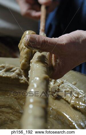 Stock Image - Close-up of a person's hand making a candle. Fotosearch