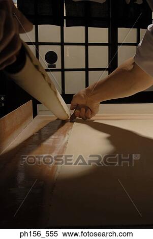 Stock Photography - Close-up of a person's hands holding a rolling pin with a rolled dough wrapped on it. Fotosearch