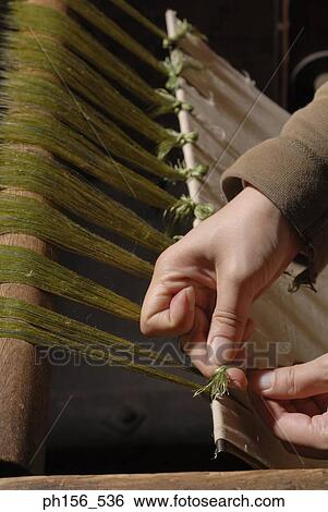 Stock Photograph - Close-up of a person's hands tying threads on a loom. Fotosearch
