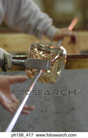 Two people molding glass with the help of an iron rod View Large Photo Image Stock Photo - Two people molding glass with the help of an iron rod. Fotosearch