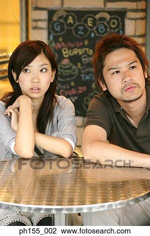Close-up of a young couple sitting at a table View Large Photo Image Stock Image - Close-up of a young couple sitting at a table. Fotosearch