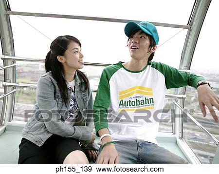 Stock Photo - Close-up of a young couple sitting in a trolley and looking away. Fotosearch