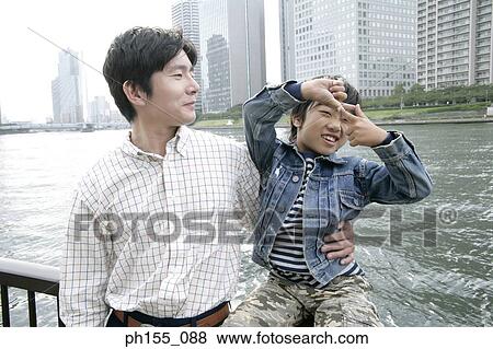 Close-up of a young man holding his son near a railing View Large Photo Image Stock Photo - Close-up of a young man holding his son near a railing. Fotosearch