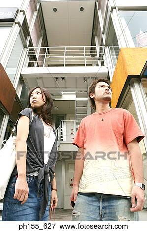 Low angle view of a young couple standing in front of an apartment View Large Photo Image Stock Photo - Low angle view of a young couple standing in front of an apartment. Fotosearch