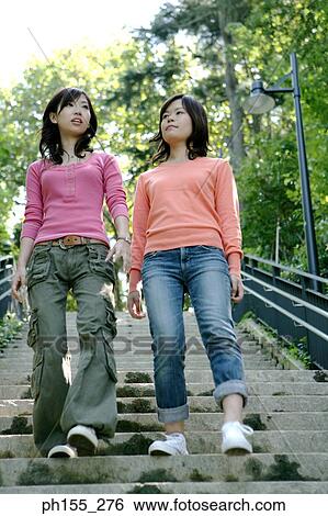 Stock Photograph - Low angle view of two young women moving down on steps. Fotosearch
