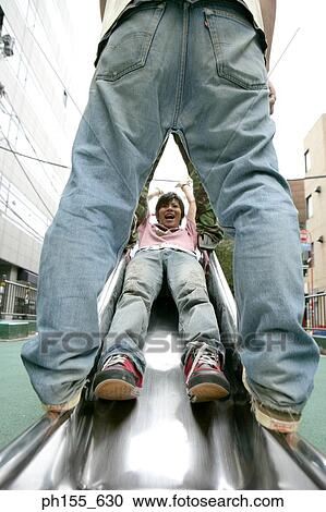 Low section view of two people standing over a young man on a slide View Large Photo Image Stock Image - Low section view of two people standing over a young man on a slide. Fotosearch