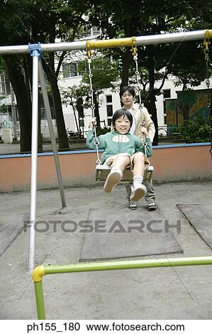 Mid adult man pushing his son on a swing View Large Photo Image Stock Image - Mid adult man pushing his son on a swing. Fotosearch