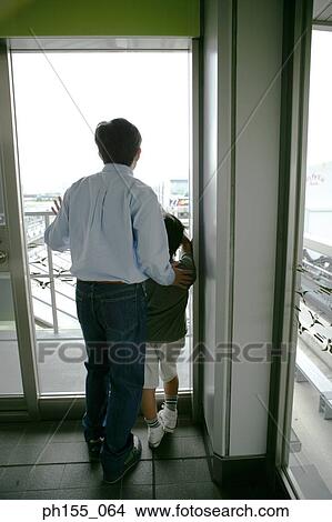 Picture - Rear view of a young man and his son standing and looking at a train. Fotosearch