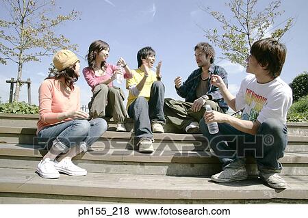 Stock Photo - Two young women and three young men sitting on steps and smiling. Fotosearch