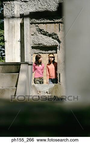 Stock Photograph - Two young women peeking through a window. Fotosearch