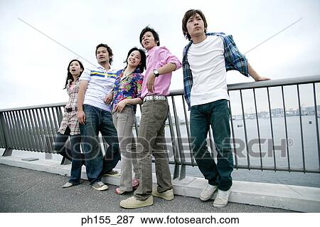 Stock Photo - Young couple standing at a railing and smiling. Fotosearch