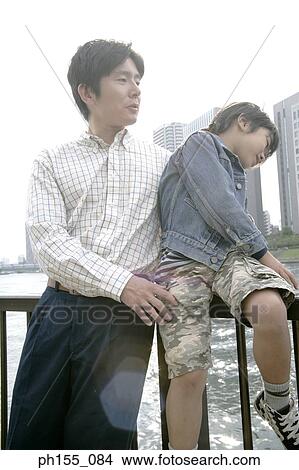 Young man and his son sitting on a railing View Large Photo Image Picture - Young man and his son sitting on a railing. Fotosearch