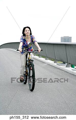 Young woman riding a bicycle View Large Photo Image Stock Image - Young woman riding a bicycle. Fotosearch