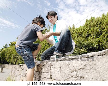 Close-up of a father helping his son climb a wall View Large Photo Image Stock Photo - Close-up of a father helping his son climb a wall. Fotosearch