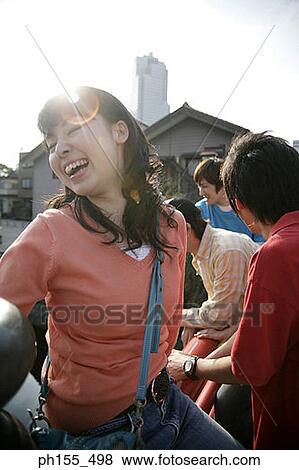 Close-up of a young woman smiling with her eyes closed and her three friends standing behind her View Large Photo Image Stock Photo - Close-up of a young woman smiling with her eyes closed and her three friends standing behind her. Fotosearch