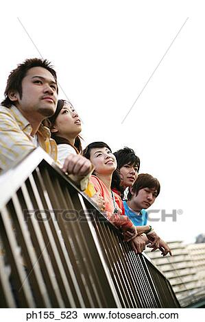 Low angle view of five people leaning on a railing and looking away View Large Photo Image Stock Image - Low angle view of five people leaning on a railing and looking away. Fotosearch