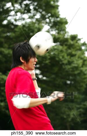 Stock Image - Side profile of a young man heading the ball. Fotosearch